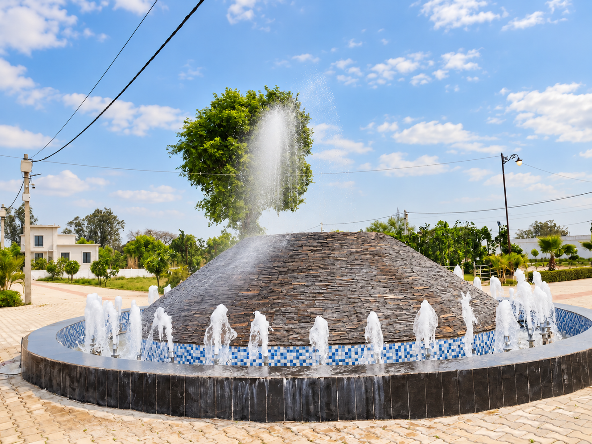 Close view of the running circular fountain with a tall central water plume and ring of smaller jets.